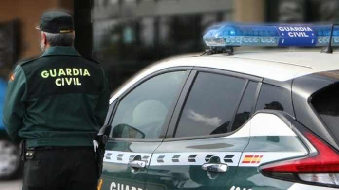 Un agente de la Guardia Civil junto a su coche patrulla